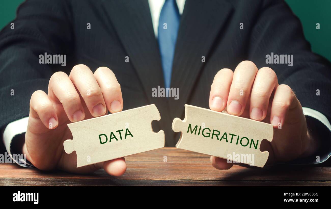 Homme d'affaires collecte des puzzles en bois avec les mots migration de données. Processus de préparation, de sélection, d'extraction de données et de transfert à partir d'un ordinateur Banque D'Images