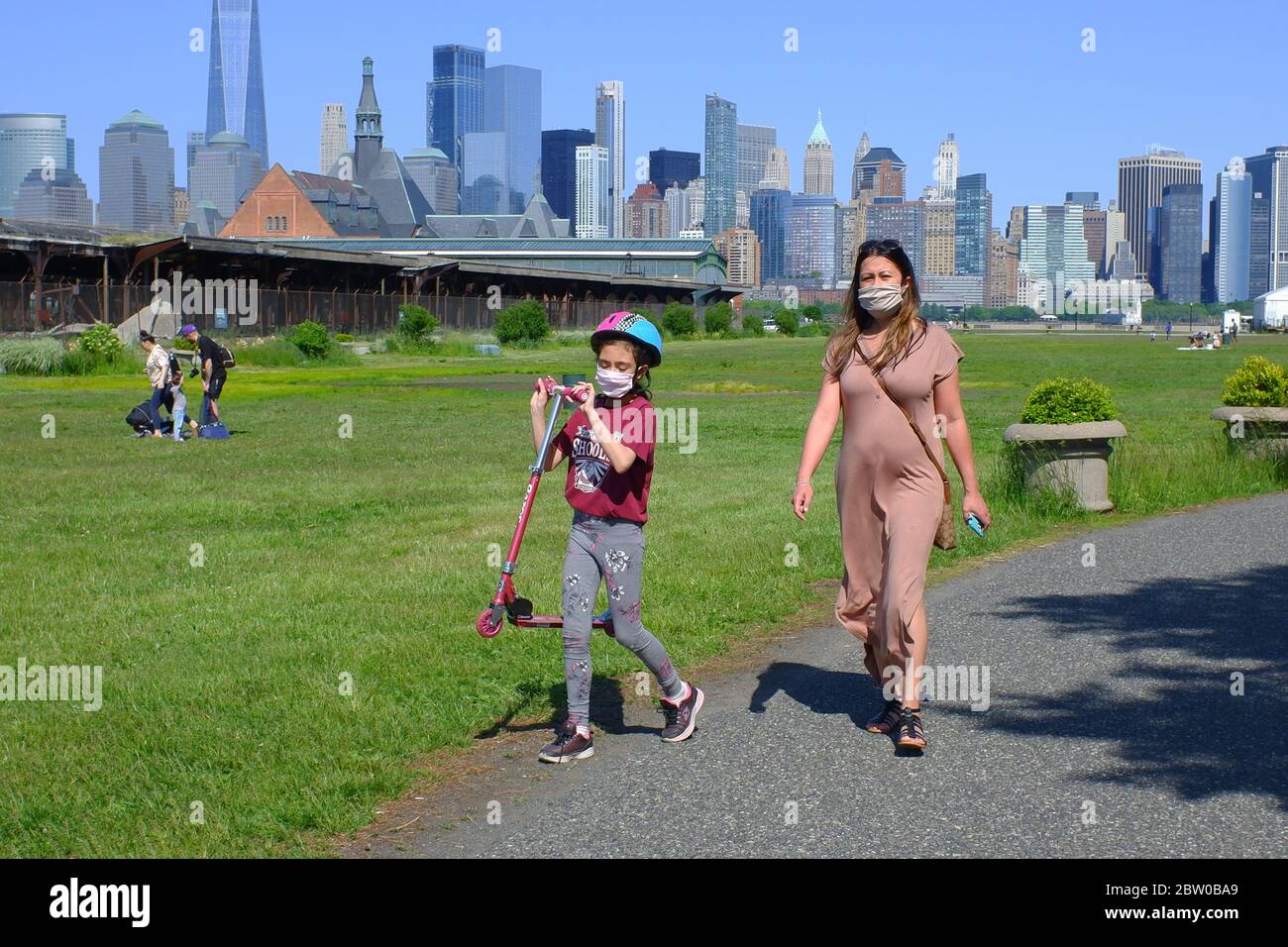 Une femme avec une jeune fille portant un masque marchant dans Liberty State Park avec la ligne d'horizon de New York City Financial District en arrière-plan.Jersey City.New Jersey.USA Banque D'Images