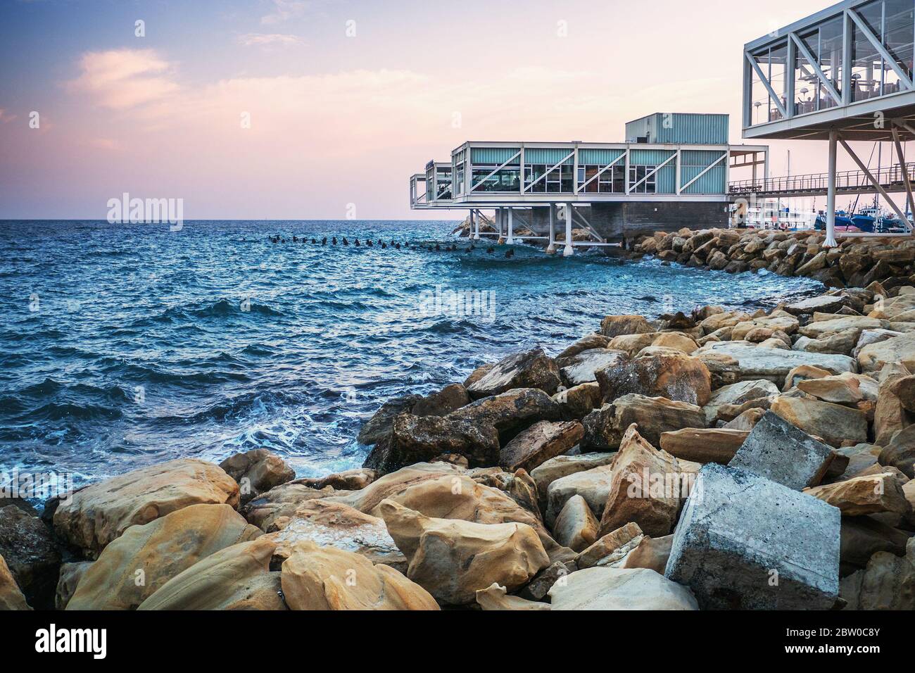 Front de mer de Limassol avec des pierres jaunes, mer bleue et cafés et bars vides au coucher du soleil, Chypre. Banque D'Images