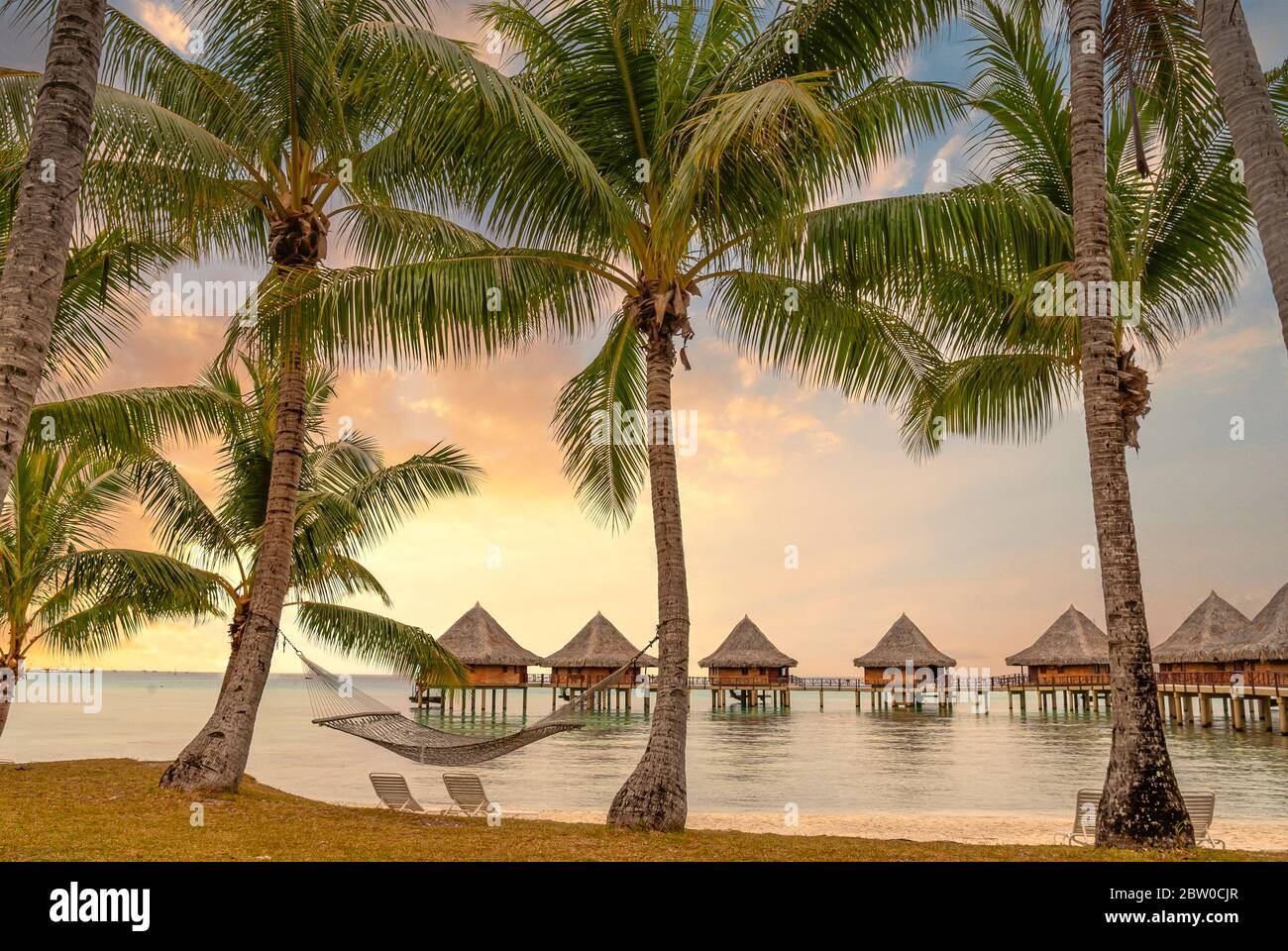 Station balnéaire au bord d'un lagon sur l'île de Tuamotu au coucher du soleil, Polynésie française Banque D'Images