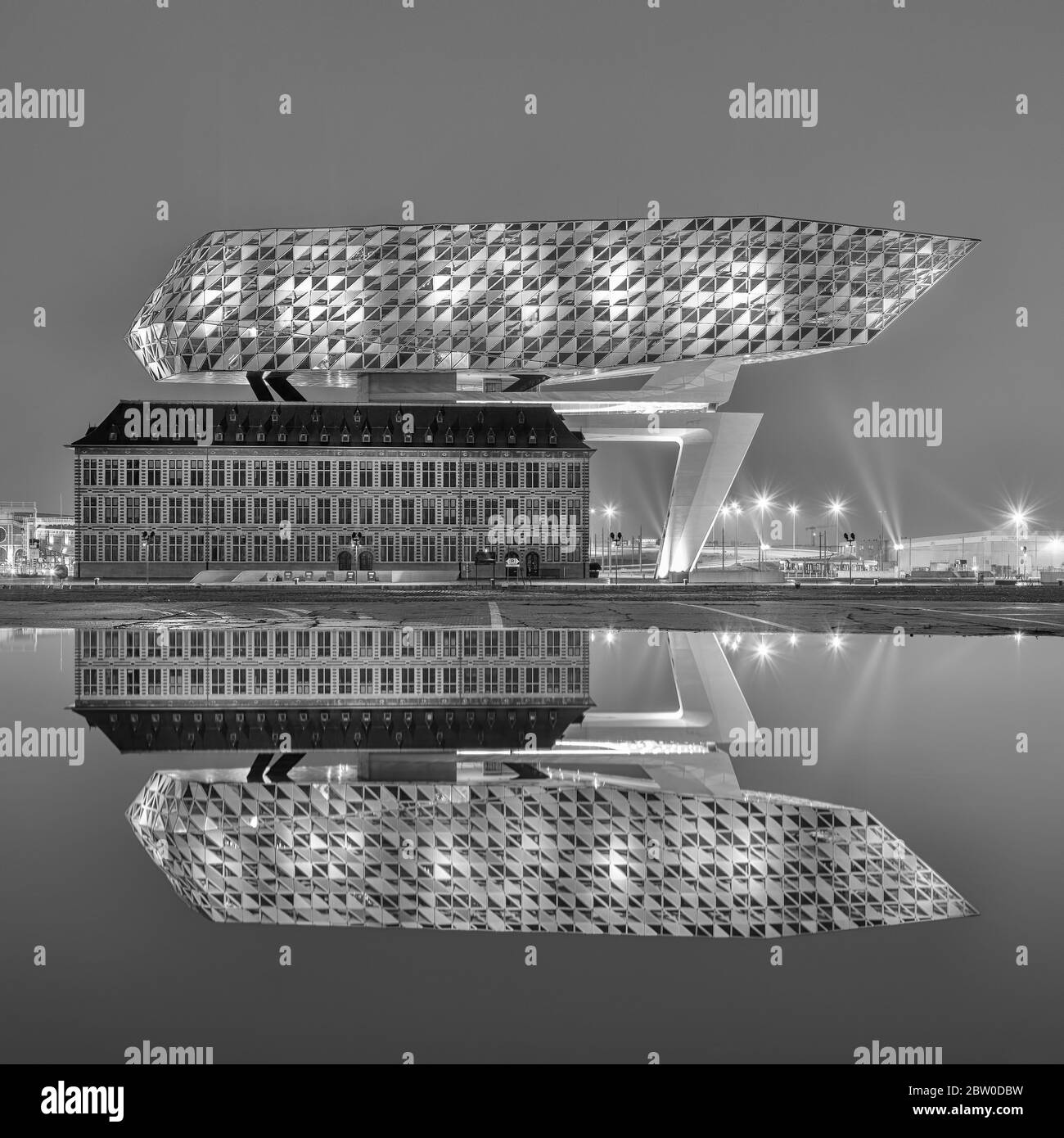 Port House la nuit se reflète dans un étang. Zaha Hadid Architects a ajouté une extension en verre à une caserne de pompiers rénovée. Banque D'Images