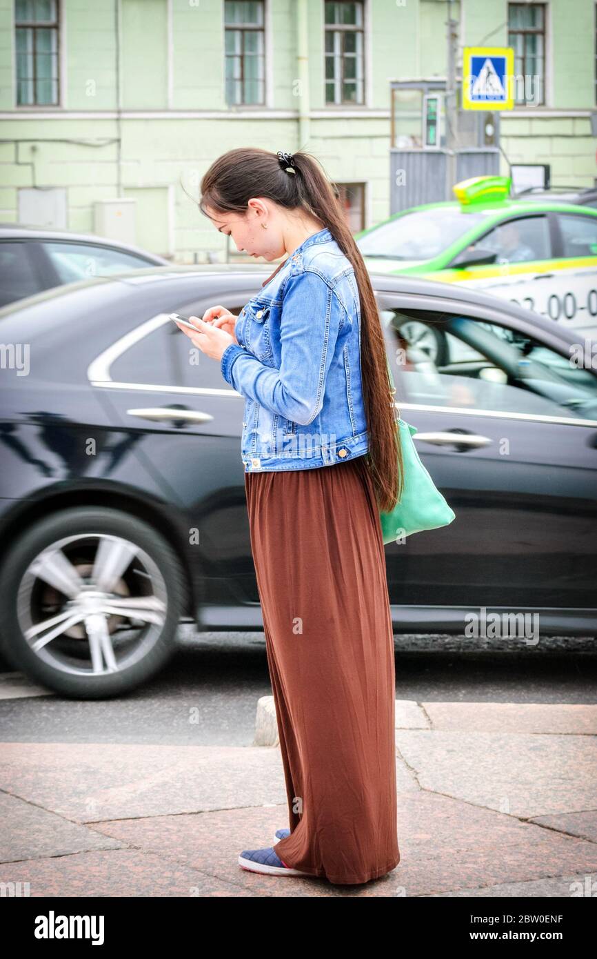 Saint-Pétersbourg, Russie, juillet 16: Une jeune fille saisit un message sur son téléphone portable en se tenant au milieu d'une rue à Saint-Pétersbourg, juillet Banque D'Images