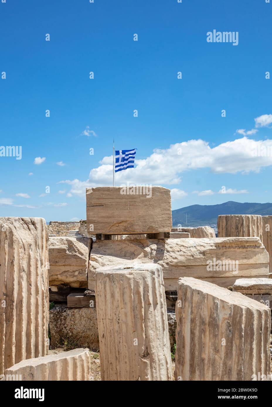Acropole d'Athènes, Grèce. Drapeau grec agitant sur le poteau, ancienne colonne reste sur fond bleu ciel, printemps jour ensoleillé. Banque D'Images