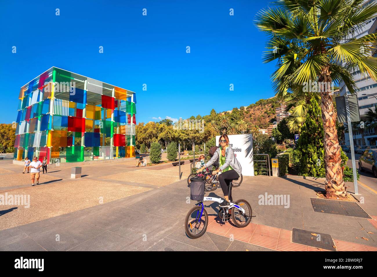 Scène de rue avec une jeune femme sur vélo contre fond de cube coloré dans le musée d'art contemporain. Malaga, Espagne Banque D'Images