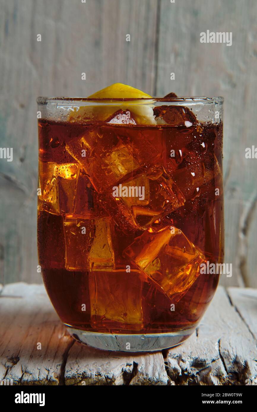 gros plan d'un verre plein de cola avec glace et citron sur une base en bois Banque D'Images