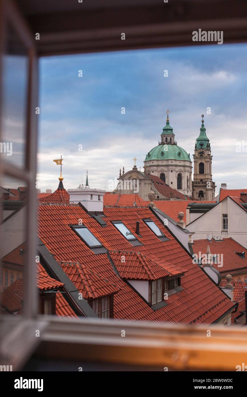 Vue sur la vieille ville de Prague par une fenêtre. Toits rouges et église historique. Banque D'Images