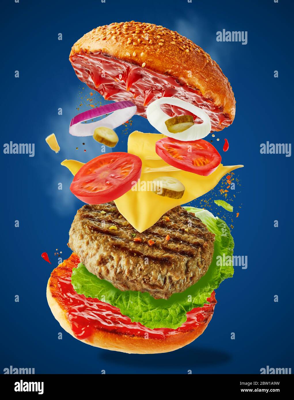 Grand hamburger maison savoureux avec des ingrédients volants sur fond bleu. Concept de la lévitation alimentaire. Banque D'Images