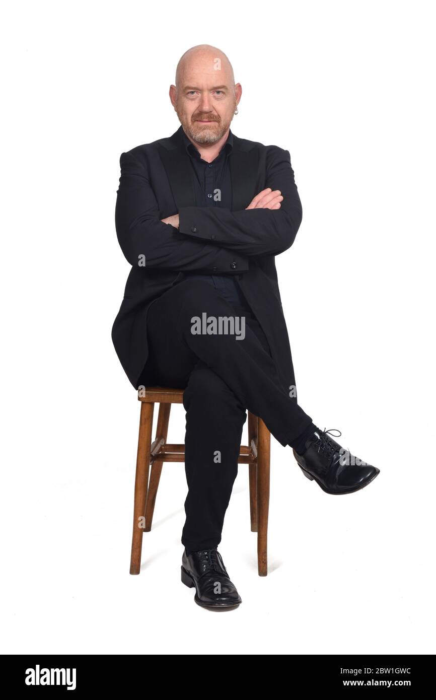 homme chauve avec les jambes et les bras croisés assis sur fond blanc Banque D'Images