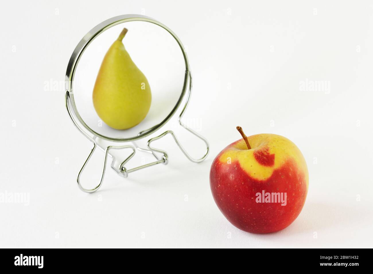 Pomme rouge regardant dans le miroir et se considérant comme une poire -  concept de dysmorphobia et de l'image de soi déformée Photo Stock - Alamy