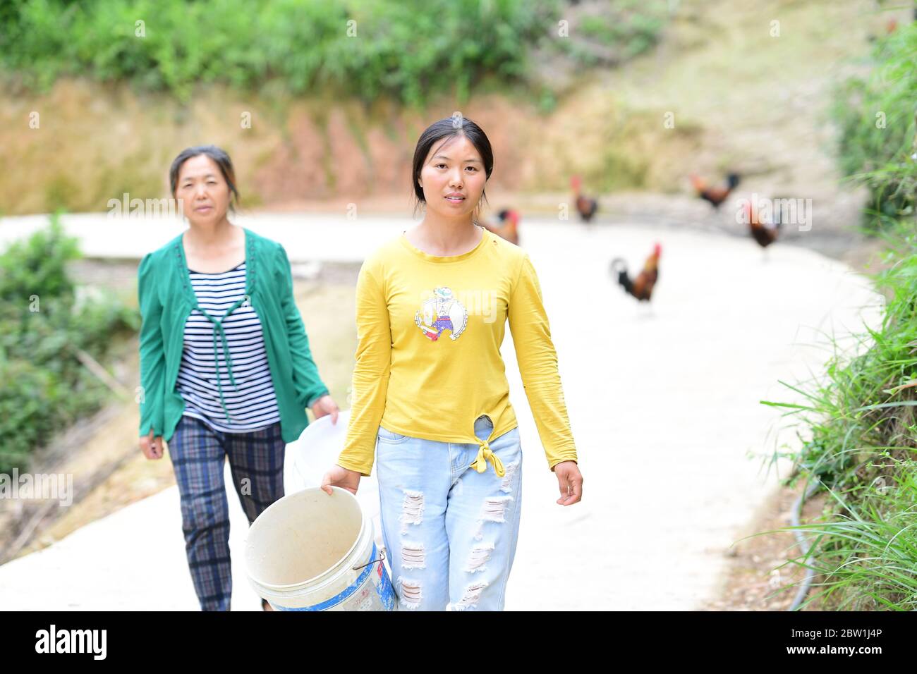 (200529) -- TIANZHU, 29 mai 2020 (Xinhua) -- Xiong Ying (R) et sa mère préparent du fourrage de poulet dans le village de Jinshan, dans le comté de Tianzhu, dans le sud-ouest de la Chine, province de Guizhou, 28 mai 2020. Xiong Ying avait travaillé comme technicienne en électronique à Guiyang avant de quitter son poste en mai 2018 et de prendre la relève de sa ferme familiale de poulet. En novembre 2019, la ferme de poulet a pris de l’expansion grâce à un fonds de lutte contre la pauvreté financé par le gouvernement. Après l'épidémie de COVID-19, Xiong a exploré d'autres façons de vendre des poulets cultivés à domicile - le programme de vente en ligne et en direct de la boutique géré par le rura, âgé de 30 ans Banque D'Images