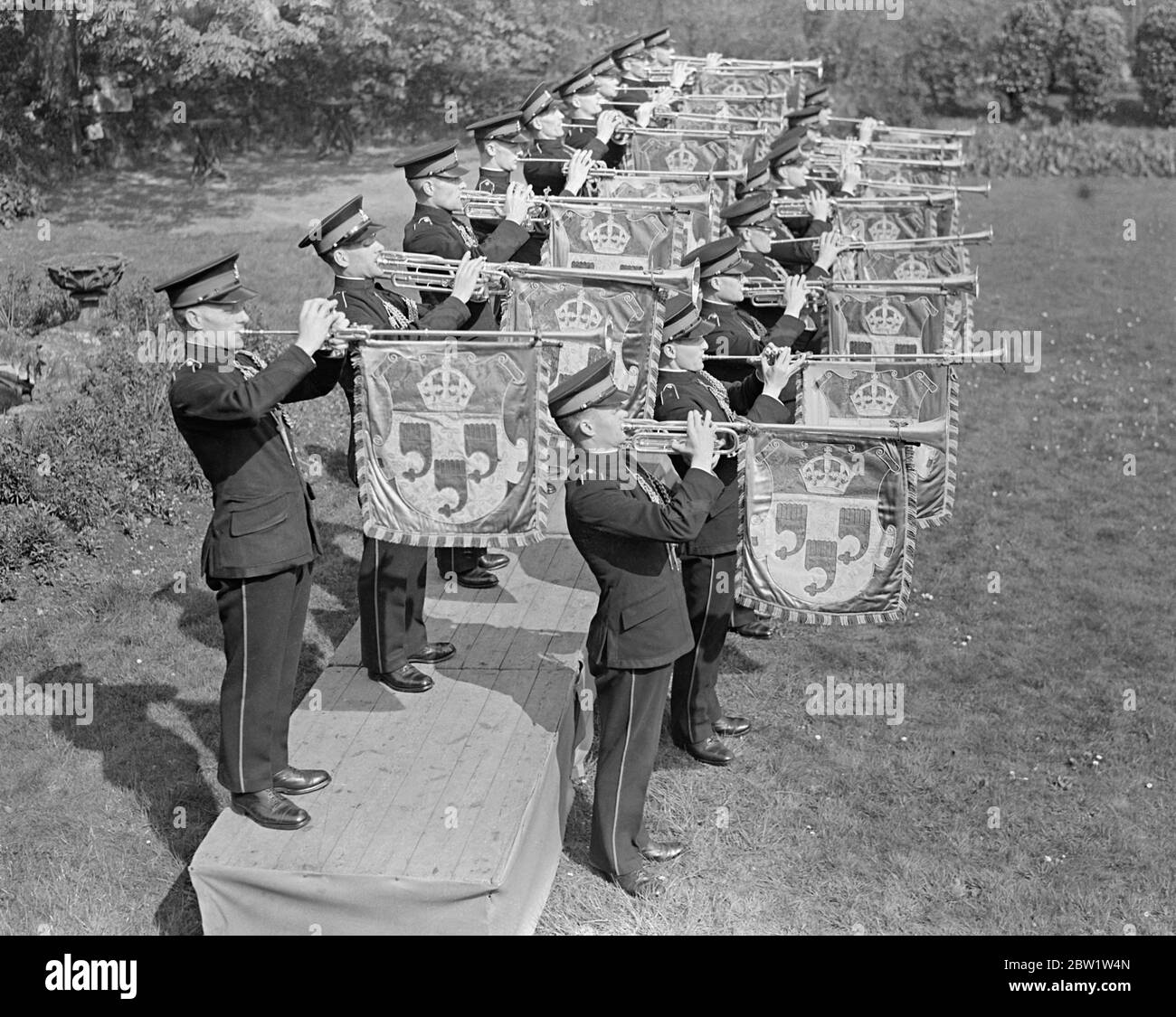 Couronnement. Les trompettistes s'exercent à Kneller Hall. Avec leurs trompettes accrochées de bannières colorées, 50 trompettistes de l'École militaire royale de musique pratique à Kneller Hall, Twickenham, les fanfares qu'ils sonneront au Coronation à l'abbaye de Westminster. Spectacles de photos : un trompettiste qui sonne le fanfare du Couronnement à Kneller Hall. 19 avril 1937 Banque D'Images