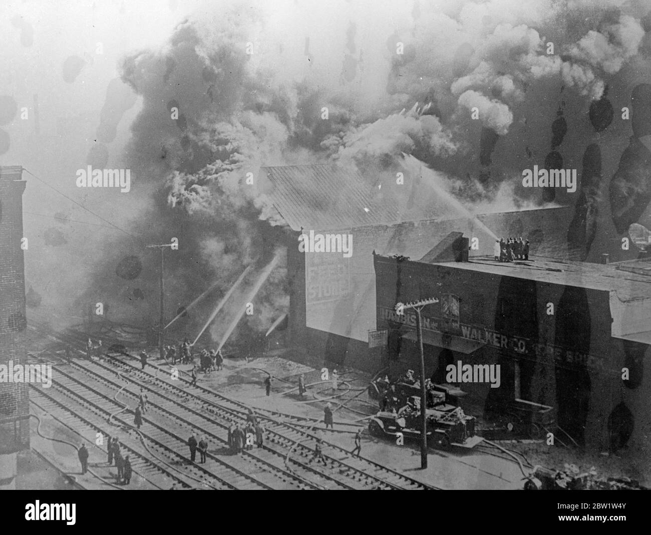 Énorme ascenseur de grain a flamber à Philadelphie. Un incendie énorme a détruit un élévateur de grain et un entrepôt à Philadelphie, en Pennsylvanie. Mais la chaleur extraordinaire du foin et de la paille brûlants a forcé les pompiers à revenir plusieurs fois et un certain nombre d'entre eux ont été surmontés. Photos montre: Volumes de fumée dense qui s'élève d'un bâtiment en feu alors que les pompiers ont lutté pour soumettre les flammes. 11 avril 1937 Banque D'Images