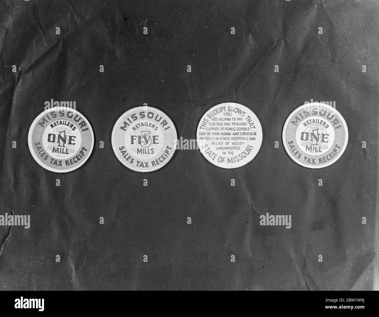 Le Missouri introduit des pièces de monnaie en papier pour payer les services sociaux. Le papier monnaie a été introduit pour la première fois dans le Missouri, aux États-Unis par un État américain. La monnaie a une valeur artificielle dans les usines ayant la valeur d'un penny. Les pièces, qui sont des disques en papier rigide de la taille des deux morceaux de shilling, sont données aux acheteurs dans le cadre de leur changement après avoir fait des achats. Les pièces sont en fait des recettes de la taxe de vente, l'argent réel étant utilisé pour l'aide au chômage, l'éducation et les programmes hospitaliers et d'autres services sociaux. Expositions de photos : le papier de monnaie du Missouri. 1er avril 1937 Banque D'Images