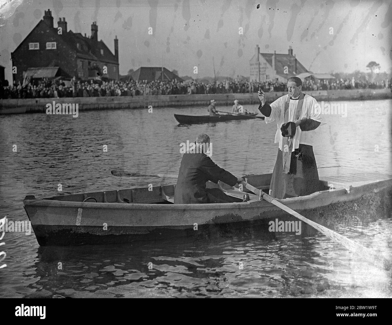 Bénédiction des eaux d'un bateau à Mudford . Après un service à l'église All Saints , le Rév Eric Dixon s'embarque à Haven Quay et a exécuté la cérémonie de Bénédiction des eaux à Mudeford , près de Christchurch , Hampshire . Des prières ont été offertes aux pêcheurs de saumon dont les moyens de subsistance dépendent de la pêche . Photos , main relevée , le Rév Eric Dixon absoud les eaux au large de Mudeford . 4 avril 1937 Banque D'Images