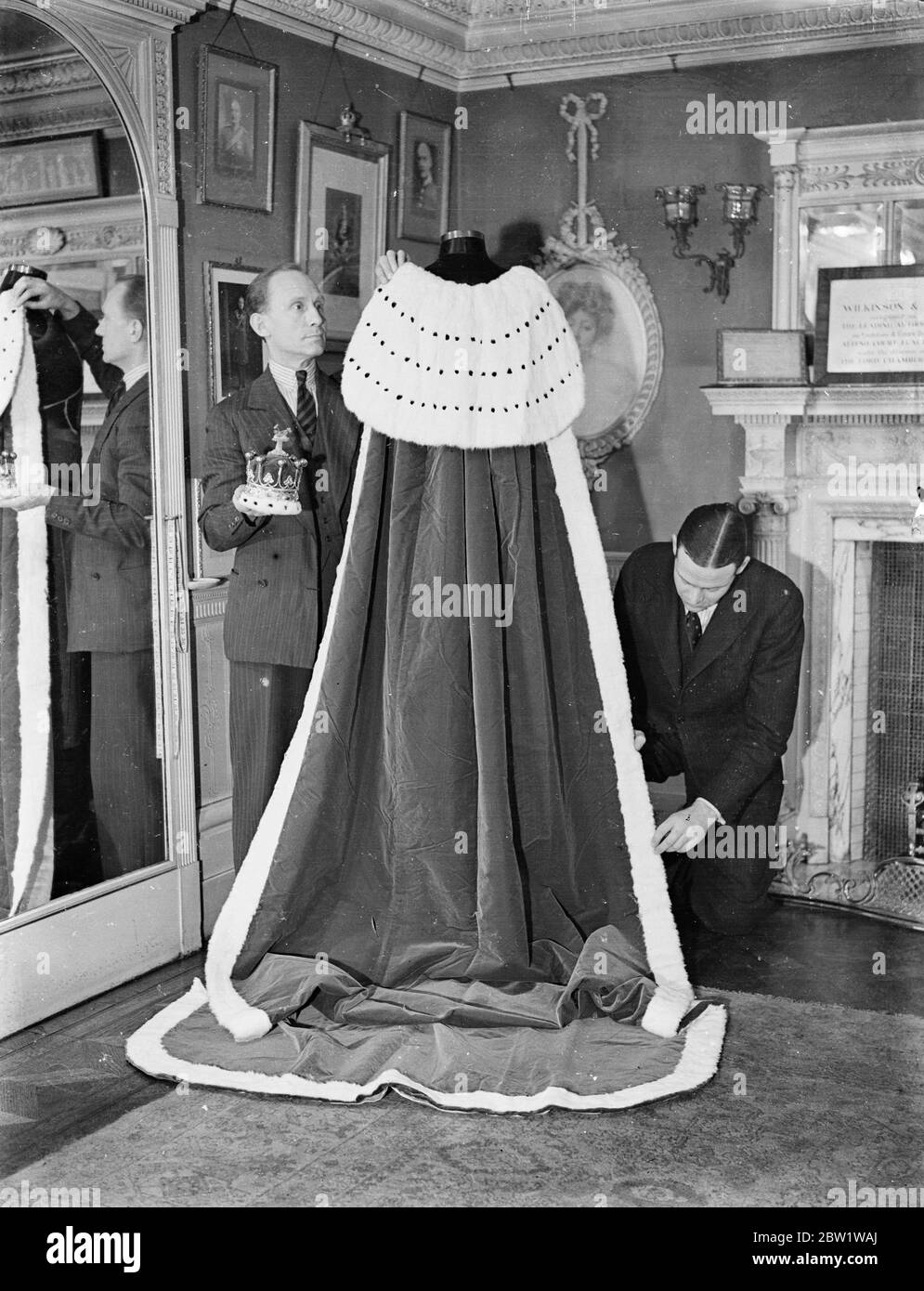 Apporter des touches de finition à vos pairs robe couronnement. Des robes rouges et blanches de velours et d'hermine qui seront portées par des pairs et des péeresses au couronnement sont fabriquées à la main dans les salles de travail du West End de Mesars, les tailleurs de Wilkinson court. Près de 20 yards de velours tissé à la main sont utilisés pour faire une robe, qui, une fois terminée, peut coûter jusqu'à 200 £. La différence dans le rang des pairs est illustrée par la variation des rangées de la fourrure noire de tir conduit dans l'ermine. Pour les péeresses, la marque distinctive est la longueur du train. Expositions de photos : apporter la touche finale à une robe de couronnement de pairs. Le thr Banque D'Images