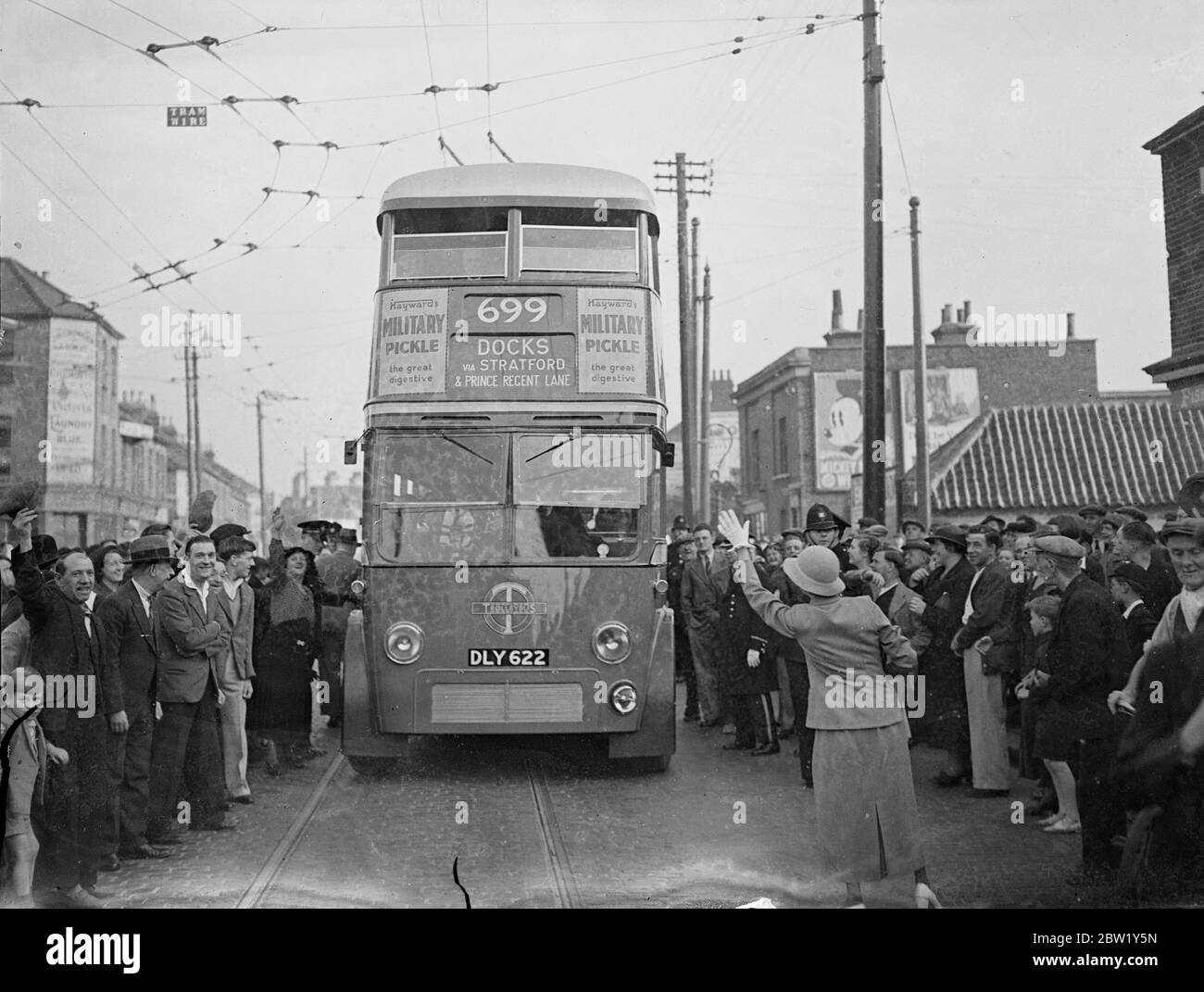 La femme maire de West Ham conduit le premier trolleybus - le plus grand changement commence dimanche matin. Mme Daisy Parsons, maire de West Ham, a conduit un trolleybus à la sortie du dépôt de Greengate Street, West Ham, tôt dimanche matin, pour inaugurer la plus grande conversion de London transport des tramways aux trolleybus. Plus de 15 000 kilomètres sont affectés. 78 tramways seront retirés et 85 trolleybus les remplaceront. Ils sont les véhicules de tourisme les plus silencieux jamais conçus. Photos : la foule qui s'est révélée tôt en l'honneur de l'occasion après le trolleybus du maire à travers les rues de Banque D'Images