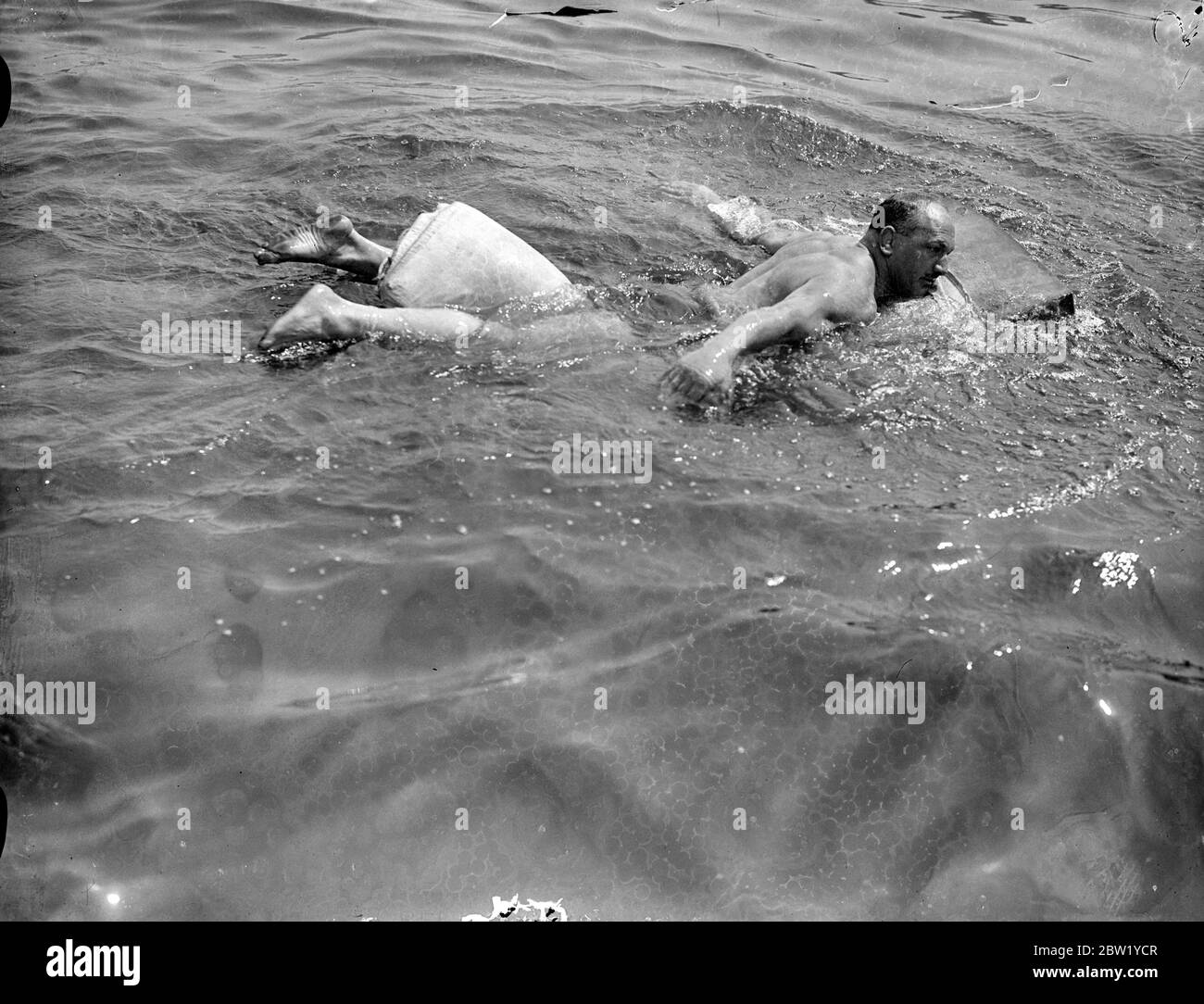 Yachtsman tente de traverser la Tamise sur un matelas. Pour prouver que le matelas en caoutchouc poreux sur lequel il dort serait utile comme un radeau d'urgence dans une épave, M. Norman Johnson, de London Yachtmen, a tenté de traverser la Tamise par un matelas. En partant d'un point près du pont Albert à Chelsea, et en utilisant les pieds et les bras comme pagaies, M. Johnson, qui est un puissant nageur, est fixé sur son matelas en caoutchouc pour la rive opposée. Le défi de M. Johnson est venu d'un autre yachtsman et il y a eu une mise de 1 £. Photos, M. Norman Johnson sur son voyage sur matelas en caoutchouc à travers la Tamise. Banque D'Images