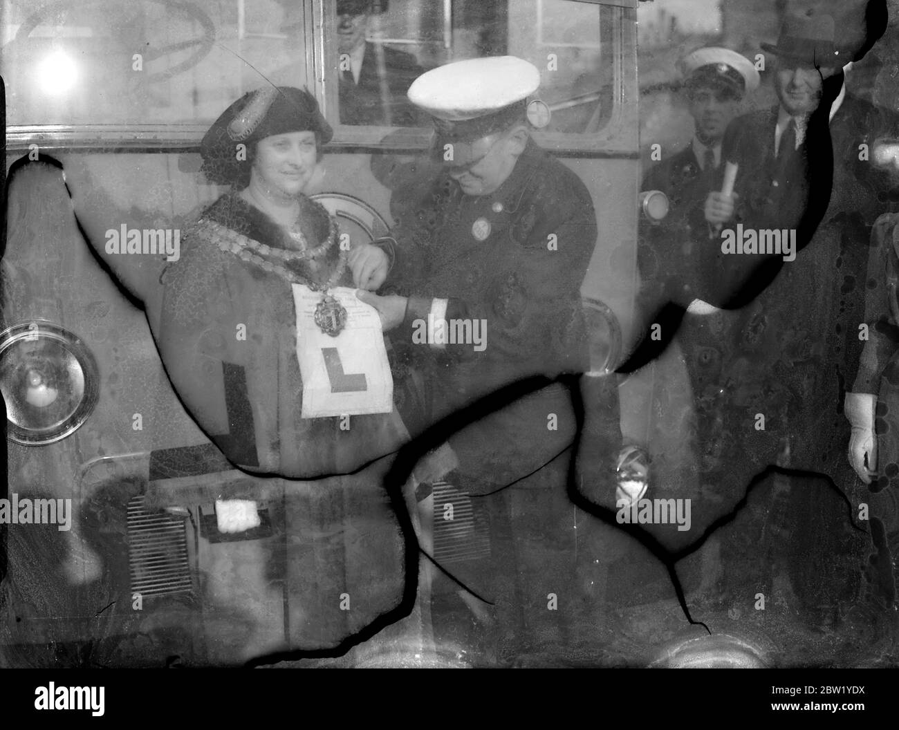 La femme maire de West Ham conduit le premier trolleybus - le plus grand changement commence dimanche matin. Mme Daisy Parsons, maire de West Ham, a conduit un trolleybus à la sortie du dépôt de Greengate Street, West Ham, tôt dimanche matin, pour inaugurer la plus grande conversion de London transport des tramways aux trolleybus. Plus de 15 000 kilomètres sont affectés. 78 tramways seront retirés et 85 trolleybus les remplaceront. Ils sont les véhicules de tourisme les plus silencieux jamais conçus. Photos: Mme Daisy Parsons, Maire de West Ham, ayant l'insigne de son apprenant accroché par son chef d'orchestre. 6 juin 1937 Banque D'Images