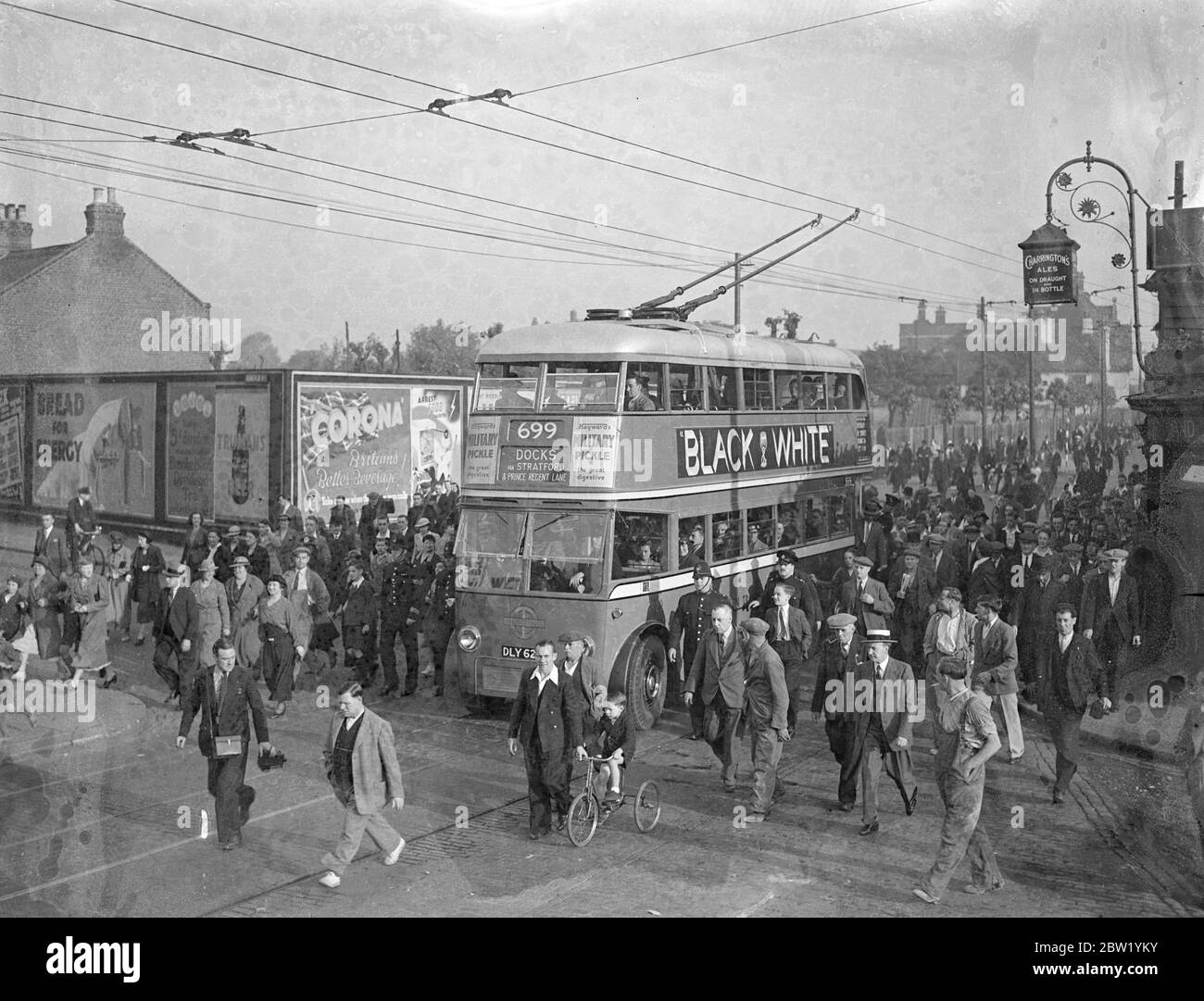 La femme maire de West Ham conduit le premier trolleybus - le plus grand changement commence dimanche matin. Mme Daisy Parsons, maire de West Ham, a conduit un trolleybus à la sortie du dépôt de Greengate Street, West Ham, tôt dimanche matin, pour inaugurer la plus grande conversion de London transport des tramways aux trolleybus. Plus de 15 000 kilomètres sont affectés. 78 tramways seront retirés et 85 trolleybus les remplaceront. Ils sont les véhicules de tourisme les plus silencieux jamais conçus. Photos : la foule qui s'est révélée tôt en l'honneur de l'occasion après le trolleybus du maire à travers les rues de Banque D'Images