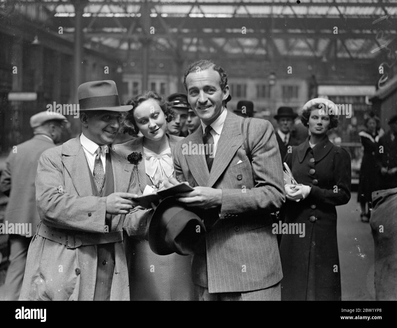 David Niven arrive d'Amérique, la « cystery » de l'engagement. David Niven, l'acteur britannique du cinéma, qui ne confirmera ni ne nie les rumeurs de son engagement envers Merle Oberon, est arrivé à Londres depuis l'Amérique sur le train 'Normandie'. Fils du regretté gén William Graham Niven et du regretté Lady Comyn Platt, Niven a conçu une commission dans le Highland Light Infantry lors d'une carrière à Stowe et Sandhurst. Après une période de globetrotting, il a été offert un test d'écran à Hollywood. Expositions de photos, David Niven, signant des autographes à l'arrivée à Waterloo. 21 juin 1937 Banque D'Images