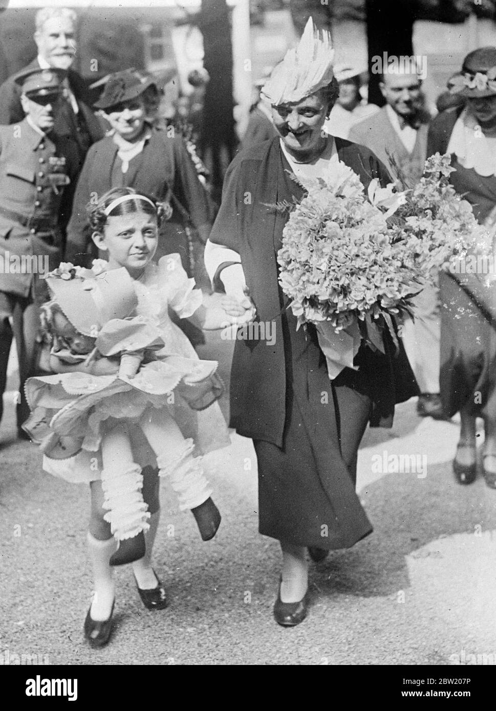 Décrite comme une prodige musicale, Annie Fresse Linard, âgée de huit ans, petite-fille du président Albert Lebrun de la République française, a donné un récital couronné de succès à l'exposition internationale de Paris. Elle porte la poupée achetée pour elle par sa grand-mère, Mme Lebrun (tenant sa main). 26 juin 1937 Banque D'Images