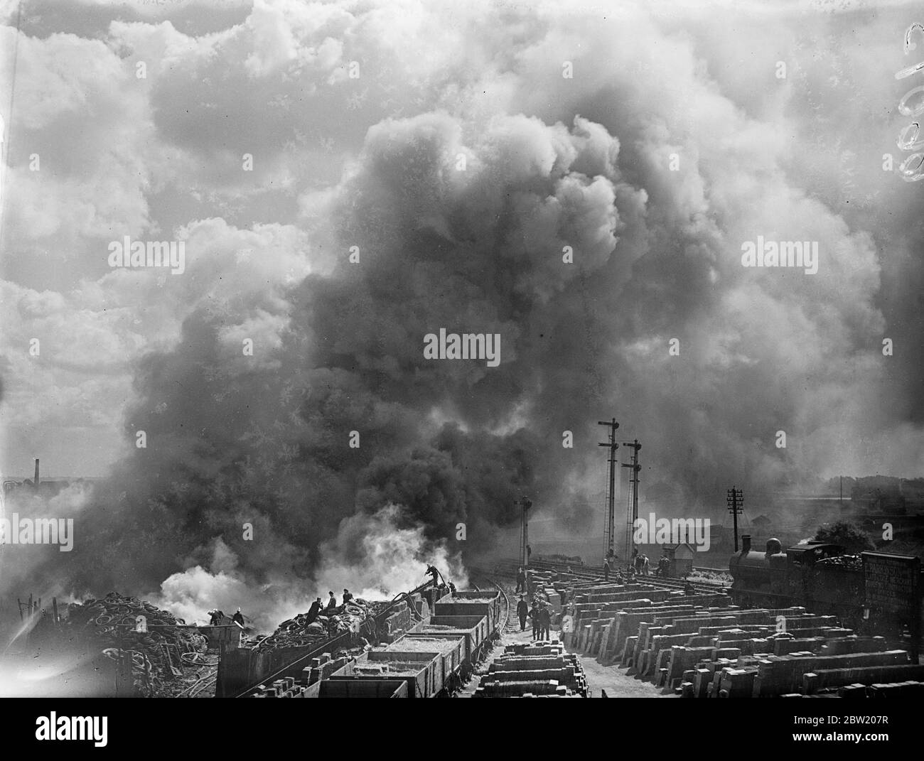 Des nuages denses de fumée s'élevant du caoutchouc brûlant alors que les pompiers combattaient le feu qui faisait rage pendant des heures dans un dépotoir de pneus de caoutchouc à Markfield Road, Tottenham. 29 juin 1937 Banque D'Images
