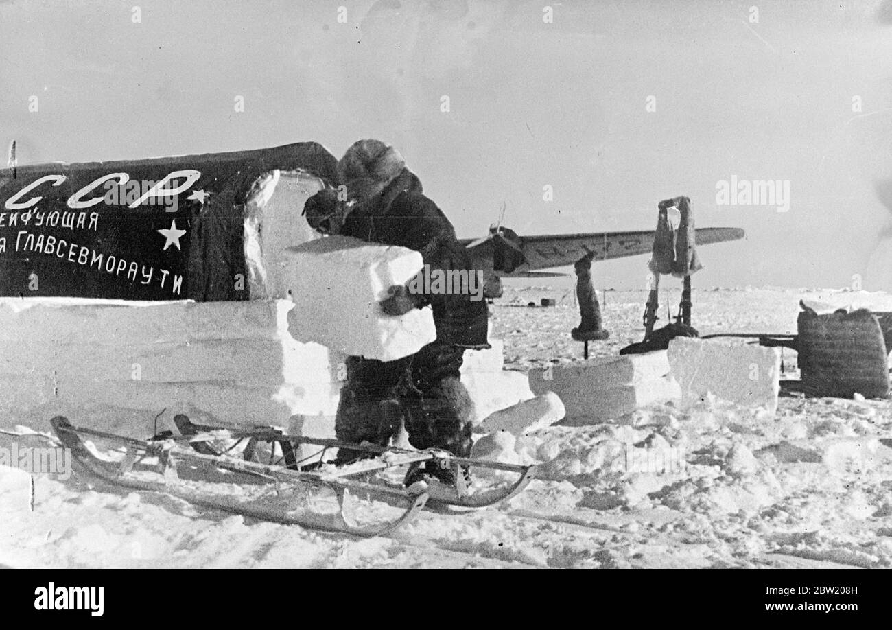Ces photos, du pôle Nord, ont été prises par avion à Moscou et de là à Londres. L'expédition scientifique soviétique dirigée par le professeur Otto Schmidt a réussi à établir un village scientifique sur une banquise dans la nature gelée à partir de laquelle des informations scientifiques précieuses et des bulletins météorologiques réguliers sont maintenant envoyés par radio pour la première fois dans l'histoire. Ivan Papanin, chef de la fête, empaquant de la glace autour d'une des tentes de la station, la transformant en une maison de glace. 30 juin 1937 Banque D'Images Ces photos, du pôle Nord, ont été prises par avion à Moscou et de là à Londres. L'expédition scientifique soviétique dirigée par le professeur Otto Schmidt a réussi à établir un village scientifique sur une banquise dans la nature gelée à partir de laquelle des informations scientifiques précieuses et des bulletins météorologiques réguliers sont maintenant envoyés par radio pour la première fois dans l'histoire. Ivan Papanin, chef de la fête, empaquant de la glace autour d'une des tentes de la station, la transformant en une maison de glace. 30 juin 1937 Banque D'Images