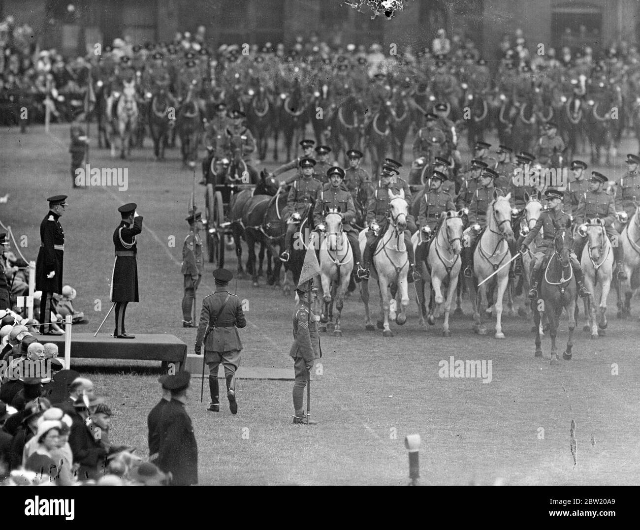 Le roi, qui a le titre ancien de capitaine général du régiment, a inspecté l'honorable Artillerie Company sur le terrain de la parade au siège, Armoury House, à Finsbury, à la fin des célébrations du 400e anniversaire. Le régiment prétend être le plus ancien en Grande-Bretagne, a reçu sa charte de Henry VIII Le roi salue comme des batteries au-delà de la base. 19 juillet 1937 Banque D'Images