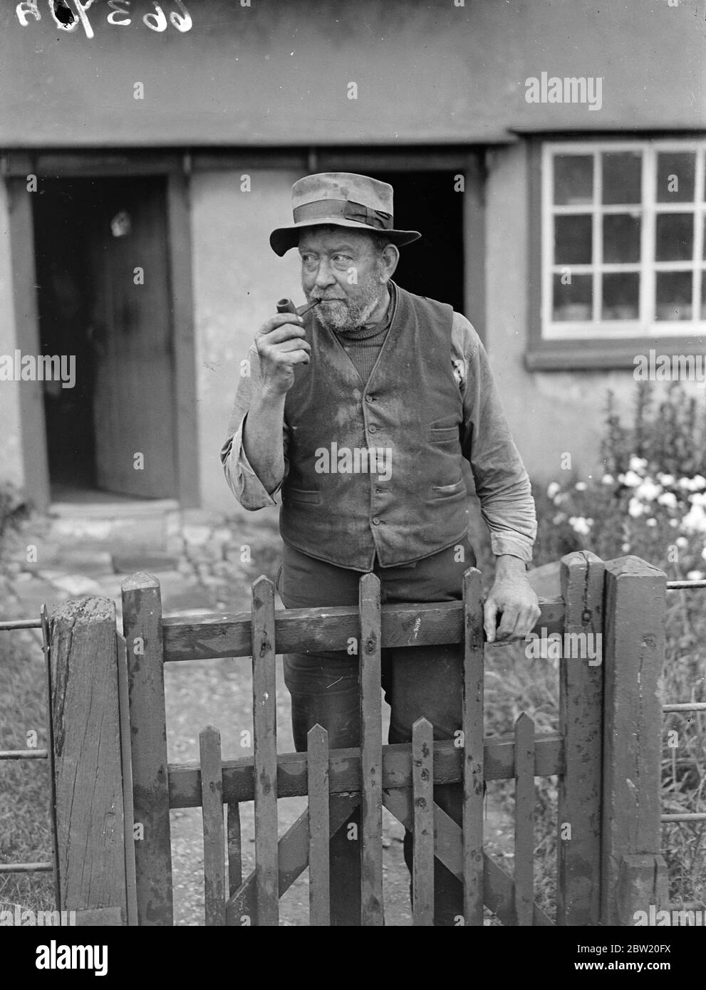 Depuis une petite auberge dans le village pittoresque de Bardfield, dans l'Essex, les anciens artisans et les personnages locaux typiques doivent diffuser aux Etats-Unis une impression de la vie de pays anglais comme elle l'a été pendant des siècles. Dans le taproom de l'Egle de propagation le wart-healer local, Uppy, deux professionnels thatchers et le professeur Harold Laski parlera dans le microphone et l'hôte de la mine, M. Harry Barnes, fermera le programme avec les derniers ordres et l'heure, monsieur, s'il vous plaît. Uppy (Charles Shephard Andrews) le guérisseur local photographié au-dessus de sa porte de jardin. Uppy peut guérir des verrues en quelques semaines sans même voir salut Banque D'Images