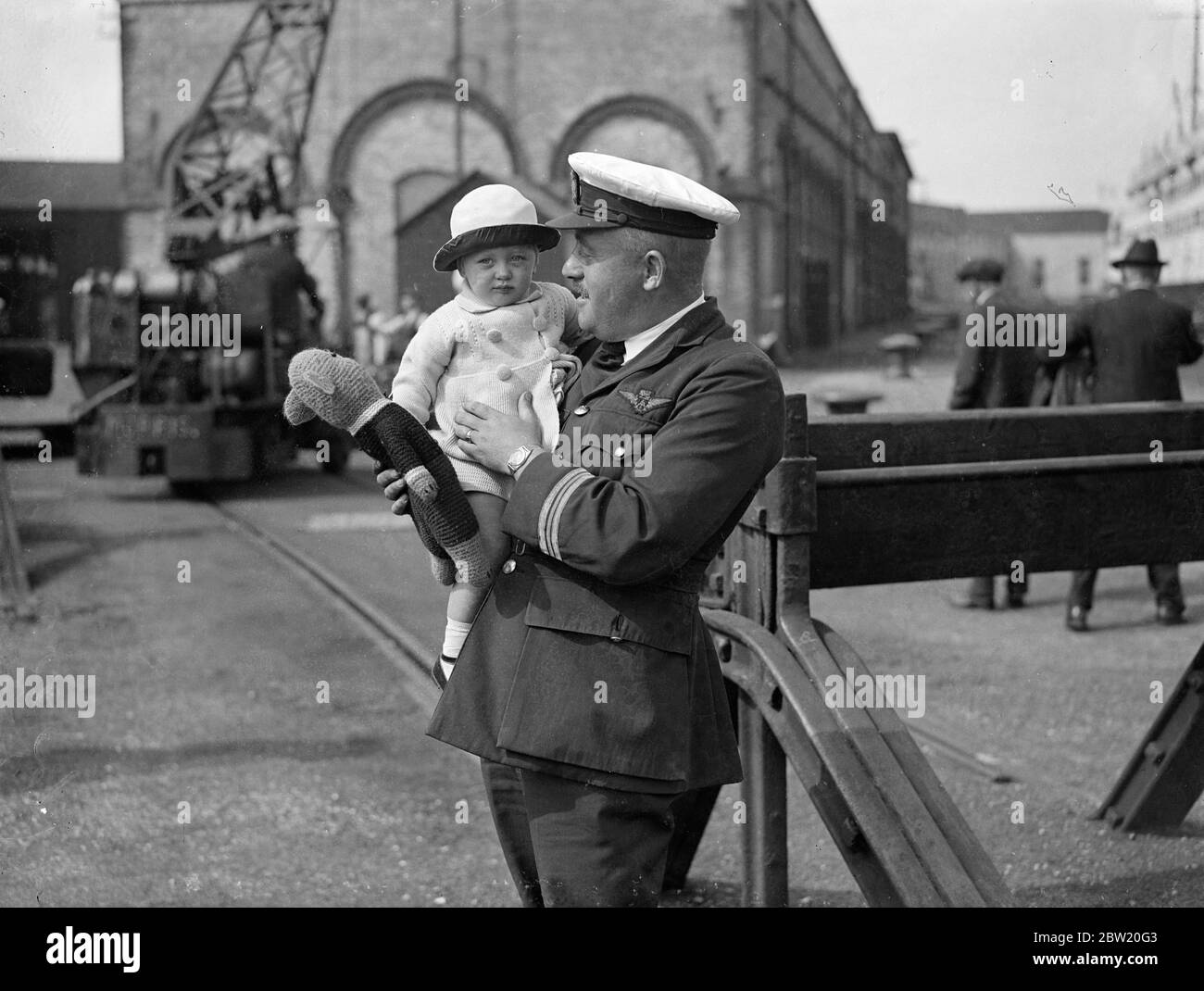 22 mois de bébé Louise Passmore dans les bras du capitaine Lock à l'arrivée à Southampton. Elle avait pris l'avion du bateau-bateau Cygnus de la Rhodésie d'Imperial Airways. 28 juin 1937 Banque D'Images