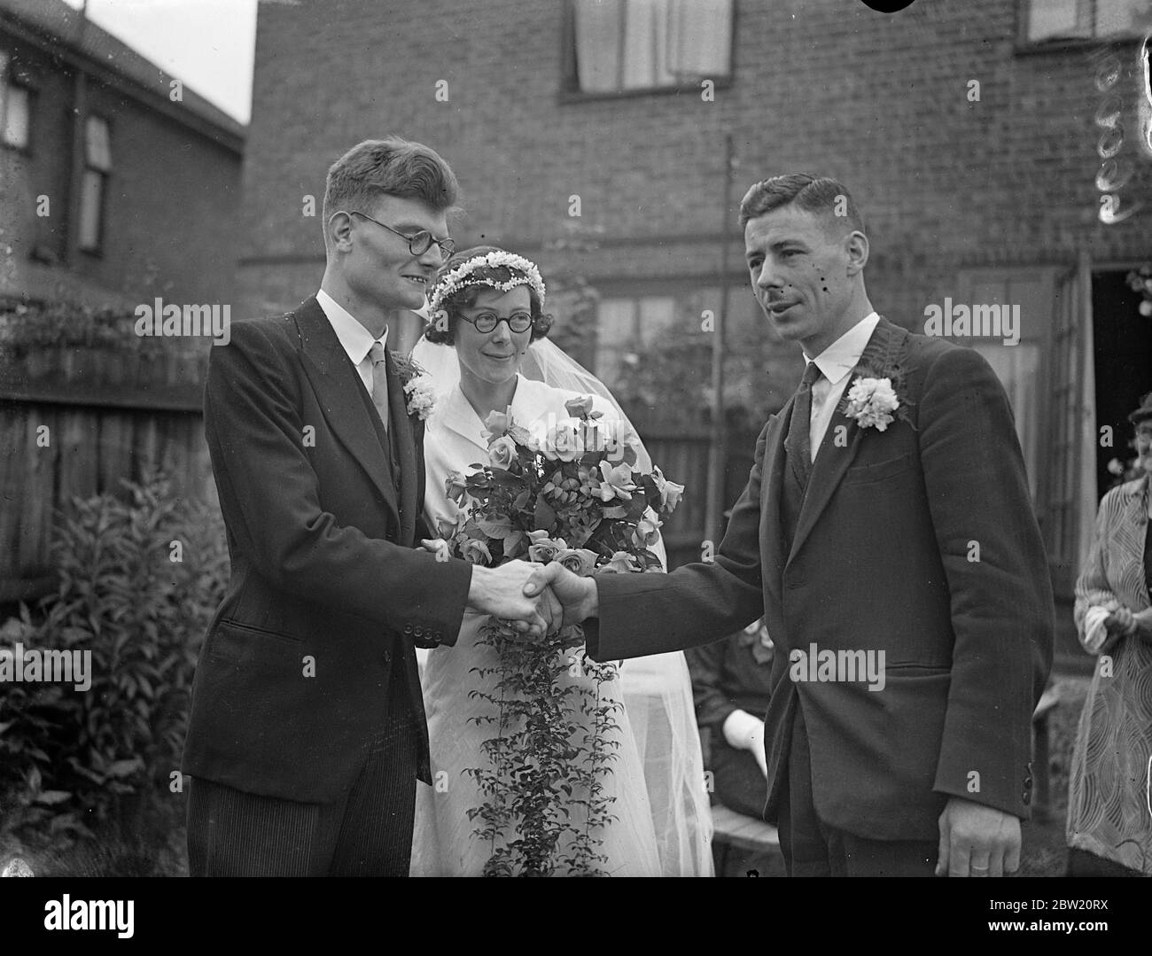 Deux familles célèbres dans le monde de la marche se sont unies lorsque Frederick John Redman, détenteur du record de marche de 10 miles, a été marié à Mlle Kathleen Avis Whitlock, sœur de la championne olympique H. H. H. Whitlock. La mariée et le marié sont félicités par Harold H. Whitlock. Après leur mariage à l'église St Jean, Algernon Road, Hendon. 27 juin 1937 Banque D'Images