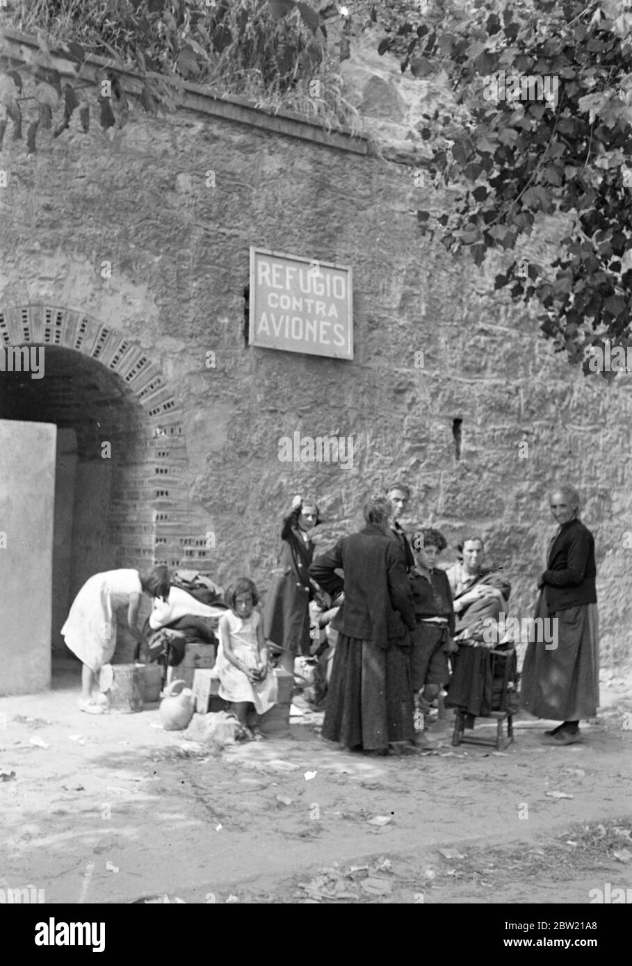 De nombreuses familles paysannes qui ont cherché refuge à Santander, dans le nord de l'Espagne, pendant les combats dans la campagne environnante quittent maintenant la ville pour retourner chez elles après la capture et l'occupation de Santander par les forces nationalistes du général Franco. Les paysans, jeunes et vieux, attendent leurs biens à l'extérieur d'un abri à l'épreuve des bombes. 28 août 1937 Banque D'Images
