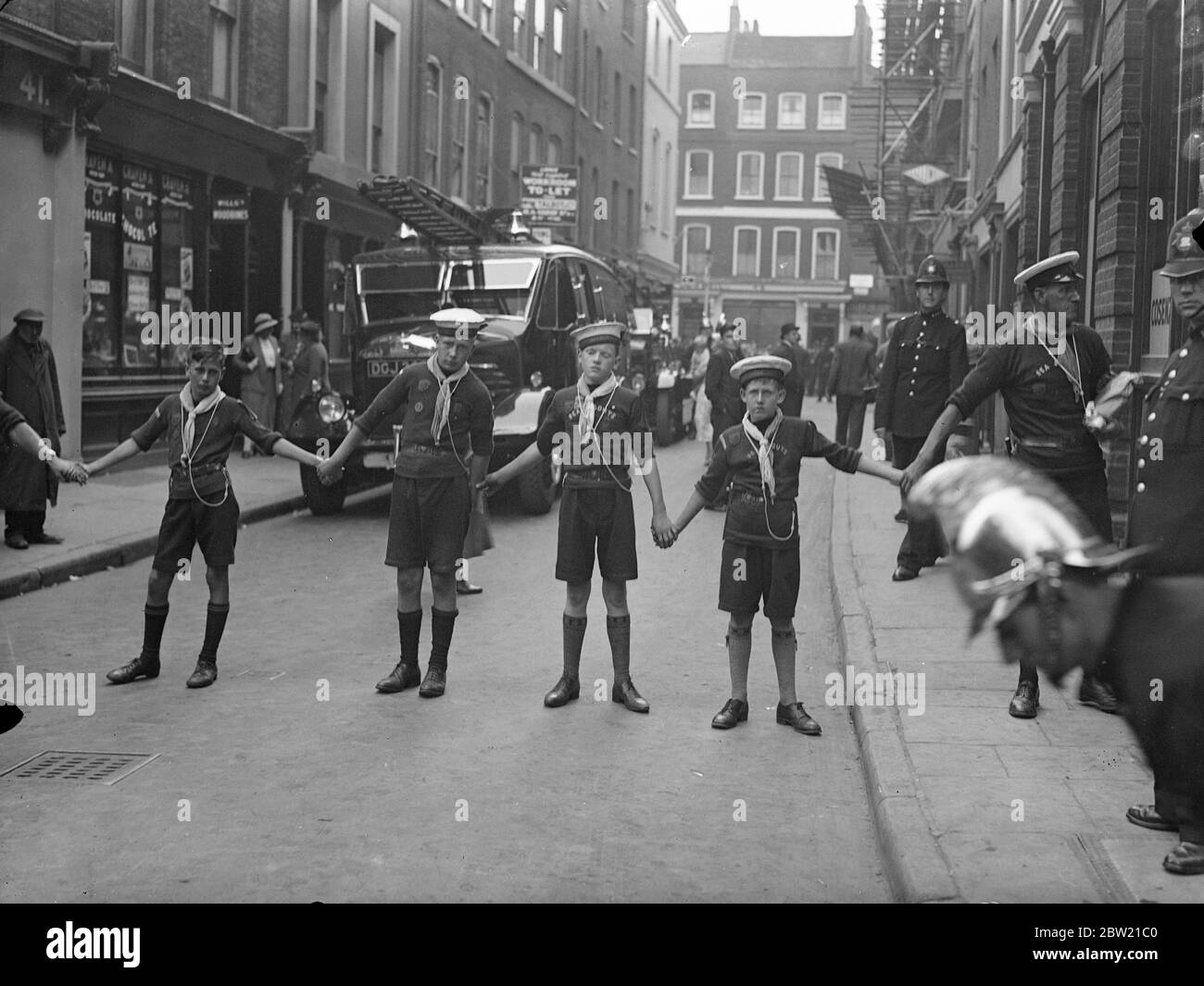 Les Sea Scouts ont dû aider la police à contrôler l'immense foule qui s'est rassemblée à Lexington Street, Piccadilly, alors que les pompiers ont secouru une femme d'un incendie dans le magasin de réparation de cycle. 27 août 1937 Banque D'Images