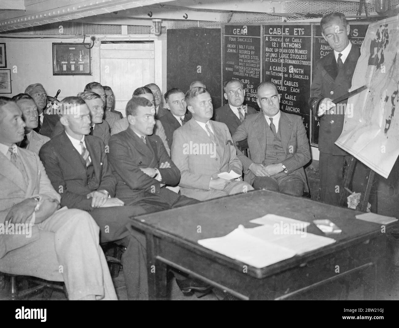 Lieutenant commandant A.S Barry avec la première classe de défense en cours les étudiants sont des officiers de la marine marchande et participent au premier cours de défense à bord du président qui est amarré dans la Tamise au large du remblai. Les cours sont conçus pour donner aux officiers de la Marine une formation sur les meilleures méthodes de défense contre les attaques en temps de guerre. 6 septembre 1937. Banque D'Images