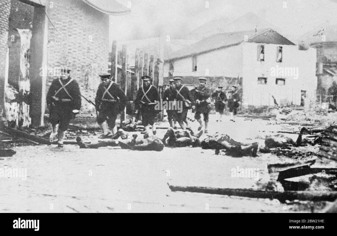 Ces photos viennent d'être reçues à Londres de Shanghai étaient l'artillerie impitoyable et les bombardements aériens par les forces japonaises et chinoises sont en ruines et tuent des milliers. Les marins japonais se fracassent un chemin parmi les morts en traversant une rue de Shanghai après de lourds bombardements. 30 août 1937 Banque D'Images