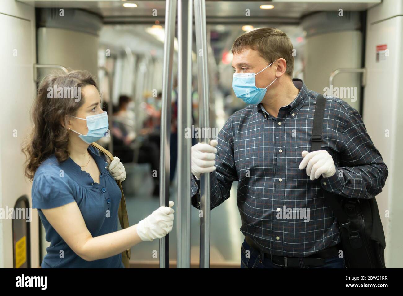 Homme et femme portant des masques médicaux jetables et des gants en  caoutchouc pour parler en métro. Précautions pendant la pandémie du  coronavirus Photo Stock - Alamy