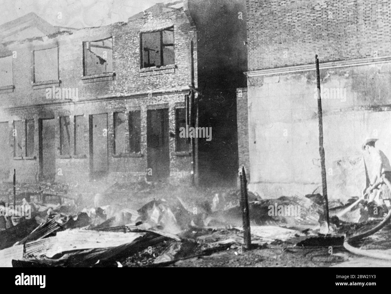 Un membre de la brigade des pompiers de l'établissement travaille sur les ruines en feu d'une maison dans le quartier de Hongkow. Ces pompiers étrangers ont porté leur travail même pendant que les obus et les bombes tombaient. Shanghai a terriblement souffert des bombardements aériens et d'artillerie du 21 septembre 1937 Banque D'Images