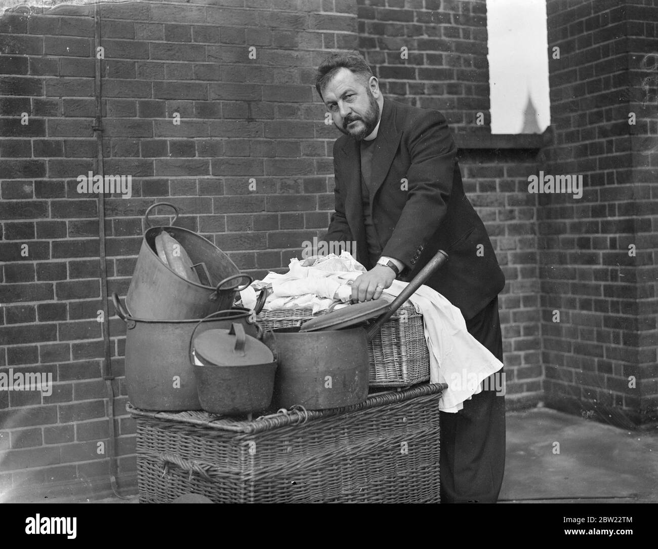 Priesr avec panier à linge et casseroles et poêles. 1937 Banque D'Images