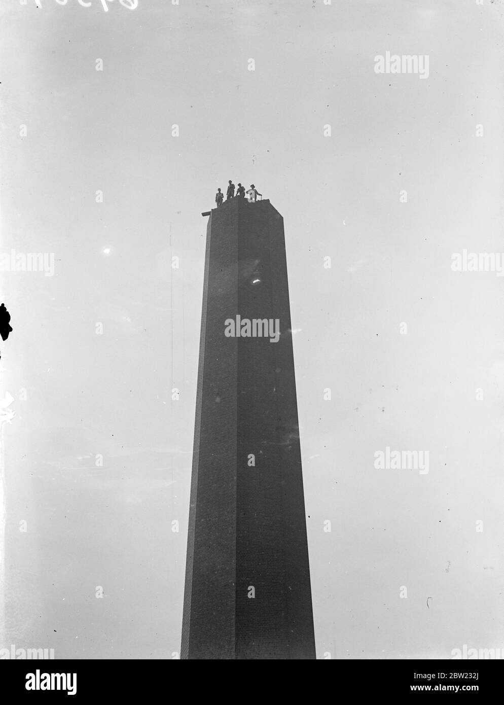 Les ouvriers perchés de façon précaires sur le rebord de la cheminée dans les locaux de South London Electricity Supply Company, à |Benjworth Road, Brixton, alors qu'ils commençaient à démolir la structure de 180 pieds brique par brique. 24 septembre 1937 Banque D'Images