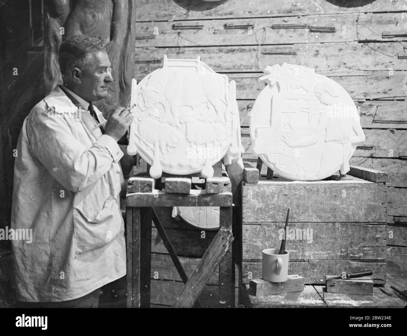 M. James Woodford travaille dans son studio de Londres sur les plaques en plâtre des portes de la nouvelle mairie de Norwich. Il a conçu les portes de l'Institut Royal des architectes britanniques, il a sculpté directement dans le plâtre dont le bronze est moulé. 14 septembre 1937. Banque D'Images M. James Woodford travaille dans son studio de Londres sur les plaques en plâtre des portes de la nouvelle mairie de Norwich. Il a conçu les portes de l'Institut Royal des architectes britanniques, il a sculpté directement dans le plâtre dont le bronze est moulé. 14 septembre 1937. Banque D'Images