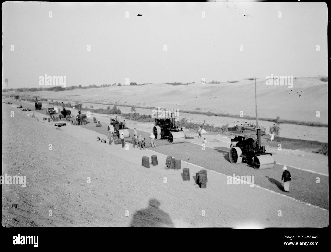 Une belle autoroute est en train d'être coupée à travers le désert égyptien pour relier le Caire à Ismailia. La route est construite sous le traité anglo-égyptien et, en plus de transporter du trafic ordinaire, facilitera grandement les mouvements de troupes. Une procession de rouleurs à vapeur sur la nouvelle route du désert entre Abu Sueir et tel el Kebir. 30 août 1937 Banque D'Images