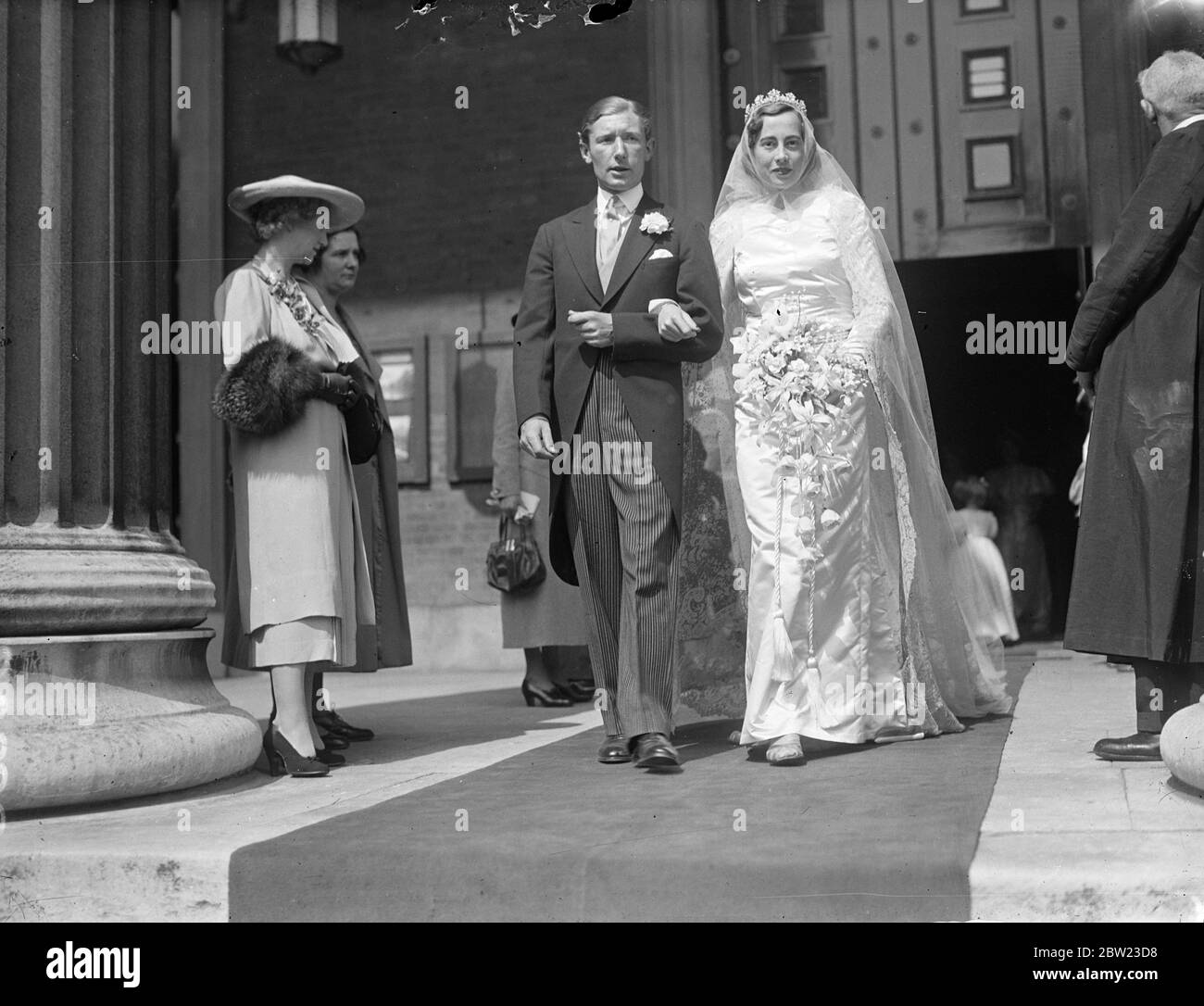 La mariée et le marié quittent l'église après la cérémonie. Le mariage de M. John Wyndham Malet des 10th Royal Hussars et Miss June Harrison-Broadley a eu lieu à l'église Saint-Pierre , Eaton Square , Londres . 8 juillet 1937. Banque D'Images