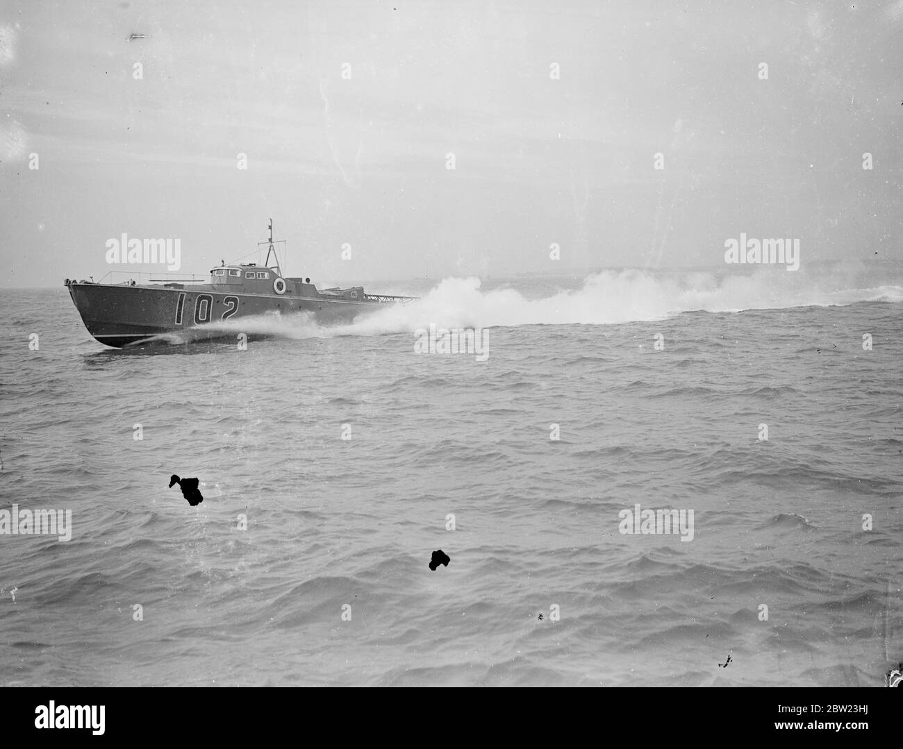 Le bateau de torpille à moteur le plus rapide au monde a fait des essais à Portsmouth. Le bateau le plus rapide et le plus puissant de son genre au monde, le bateau à torpille à moteur 102 (MTB 102) a été testé à vitesse à Portsmouth, où il a été construit par Vosper Ltd. , équipé de torpilles de 21 pouces, capable de tirer en avant ou en arrière, le bateau est conduit par un moteur marin de 1000 ch développant une vitesse de 47.6 kn. Le bateau peut faire une attaque de torpille à pratiquement n'importe quelle vitesse, et pour les attaques dans l'obscurité ou le fukesscreen peut naviguer silencieusement à 10 kn sur les moteurs auxiliaires. 15 février 1938 Banque D'Images