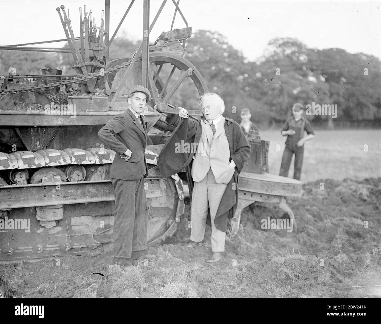 Utilisant un nouveau gyrotimon, une charrue pour creuser, et des hommes travaillant jour et nuit. M. Lloyd George, politicien vétéran qui a maintenant 75 ans, transforme en un temps record 160 acres de terres inutilisées en un jardin de marché. La terre, qui rejoint sa ferme à Churt, Surrey, n'a pas été intensément cultivée depuis de nombreuses années, mais déjà la moitié de la superficie est prête pour la plantation. Les hommes travaillent la nuit par projecteur. Photos: Lloyd George, cheveux blancs balayés par le vent, donnant des instructions à l'opérateur du gyrotimon sur sa nouvelle ferme. 17 octobre 1938 Banque D'Images