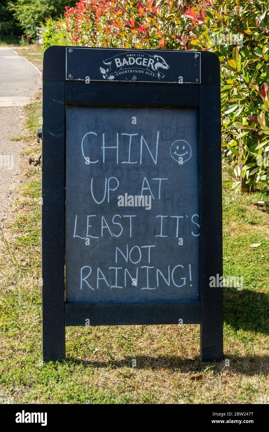 Panneau amusant devant le pub Onslow Arms disant que Chin Up au moins, il ne pleut pas ! Pendant la pandémie du coronavirus Covid-19, Loxwood, West Sussex, Royaume-Uni Banque D'Images