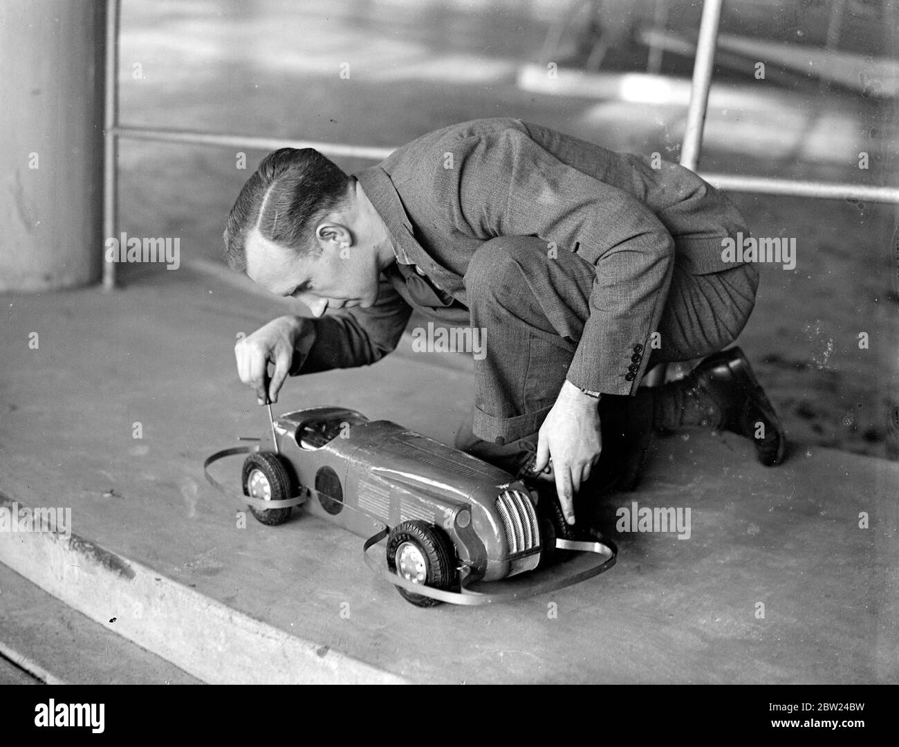 Des modèles de voitures pour avoir leur propre rencontre de course à Londres. La course de voitures Midget avec une vengeance sera vu quand la première réunion de la saison de l'Association des courses de voitures modèles aura lieu à Kensington le week-end prochain. Certaines voitures modèles. Le train peut atteindre 50 km/h. Ils sont entraînés par un plastique ou un horlogerie. Séances photo, M. R. V Daley prépare sa voiture modèle pour la réunion. Le petit véhicule est conduit par plus de 100 yards d'élastique. 3 octobre 1938 Banque D'Images