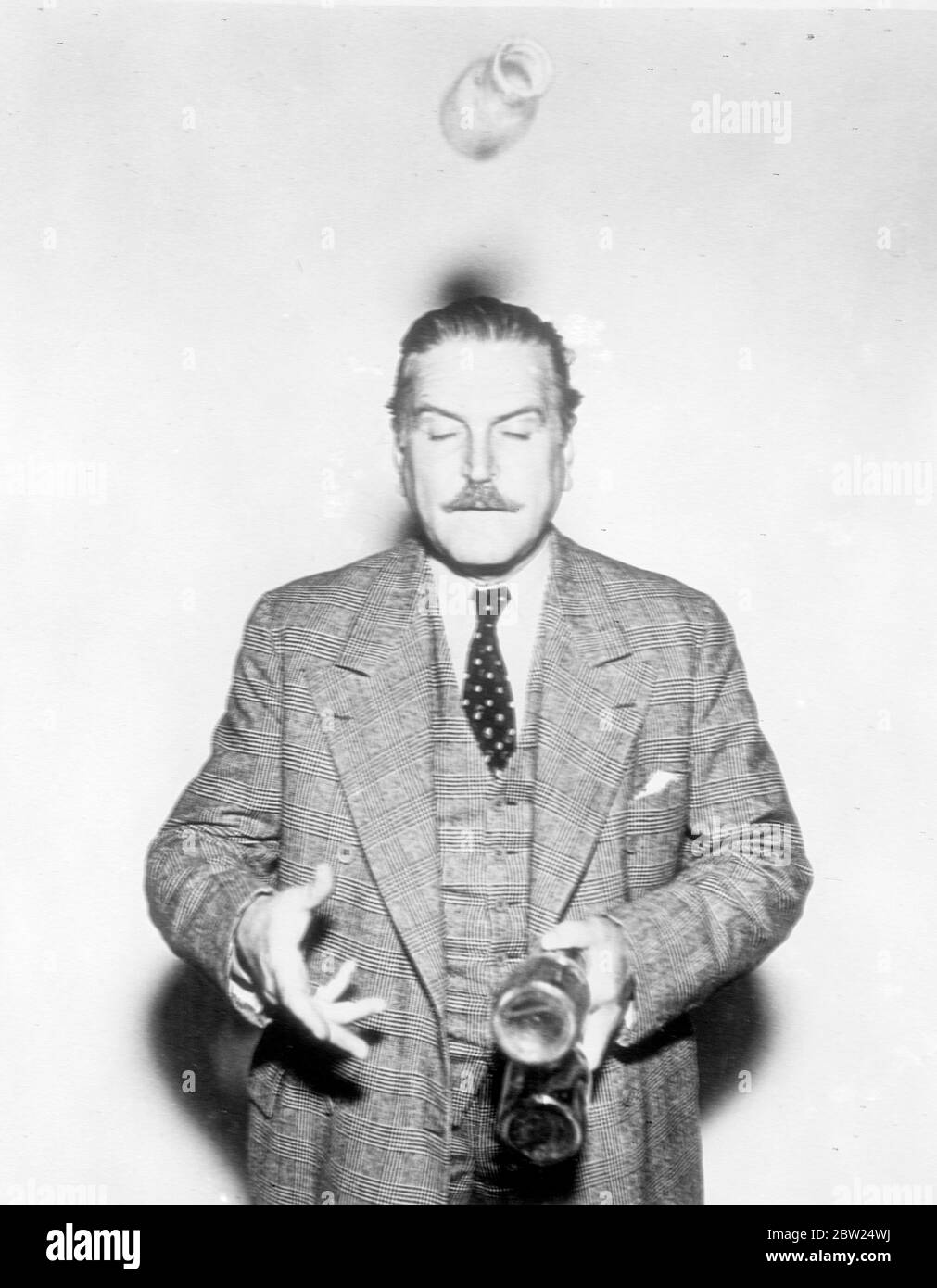 L'acteur du film tourne le conjuré et obtient une surprise. Avec trois bouteilles de lait vides et beaucoup d'espoir, Frank Morgan, l'un des meilleurs joueurs d'Hollywood, célèbre pour ses joviaux types, dépeint à l'écran, a pris l'occasion de divertir ses amis avec un jeu de jonglerie. Sa confiance était mal placée, cependant, car il a perdu le contrôle d'une bouteille et ne l'a trouvée que lorsqu'elle le frappe sur la tête. Des expositions de photos, Frank Morgan épaules haussé et les yeux serrés fermés, perd cette bouteille et les blancs appréhende de l'accident. Banque D'Images