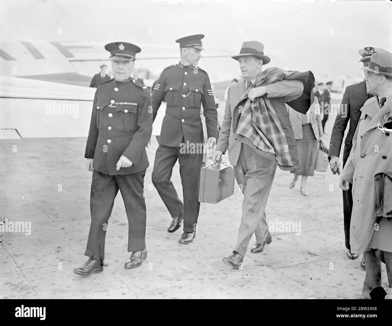 Le capitaine Thomas Kendrick, l'officier britannique de contrôle des passeports à Vienne, qui a été arrêté par la police secrète allemande et accusé d'espionnage, est arrivé à l'aérodrome de Croydon après sa libération. Le capitaine Kendrick a été libéré à condition qu'il quitte l'Allemagne immédiatement. Il est retourné en Angleterre via Budapest et doit faire un rapport personnel au gouvernement britannique sur son arrestation. Expositions de photos, le capitaine Thomas Kendrick, escorté par aérodrome, s'il vous plaît à son arrivée à Croydon. 22 août 1938 Banque D'Images