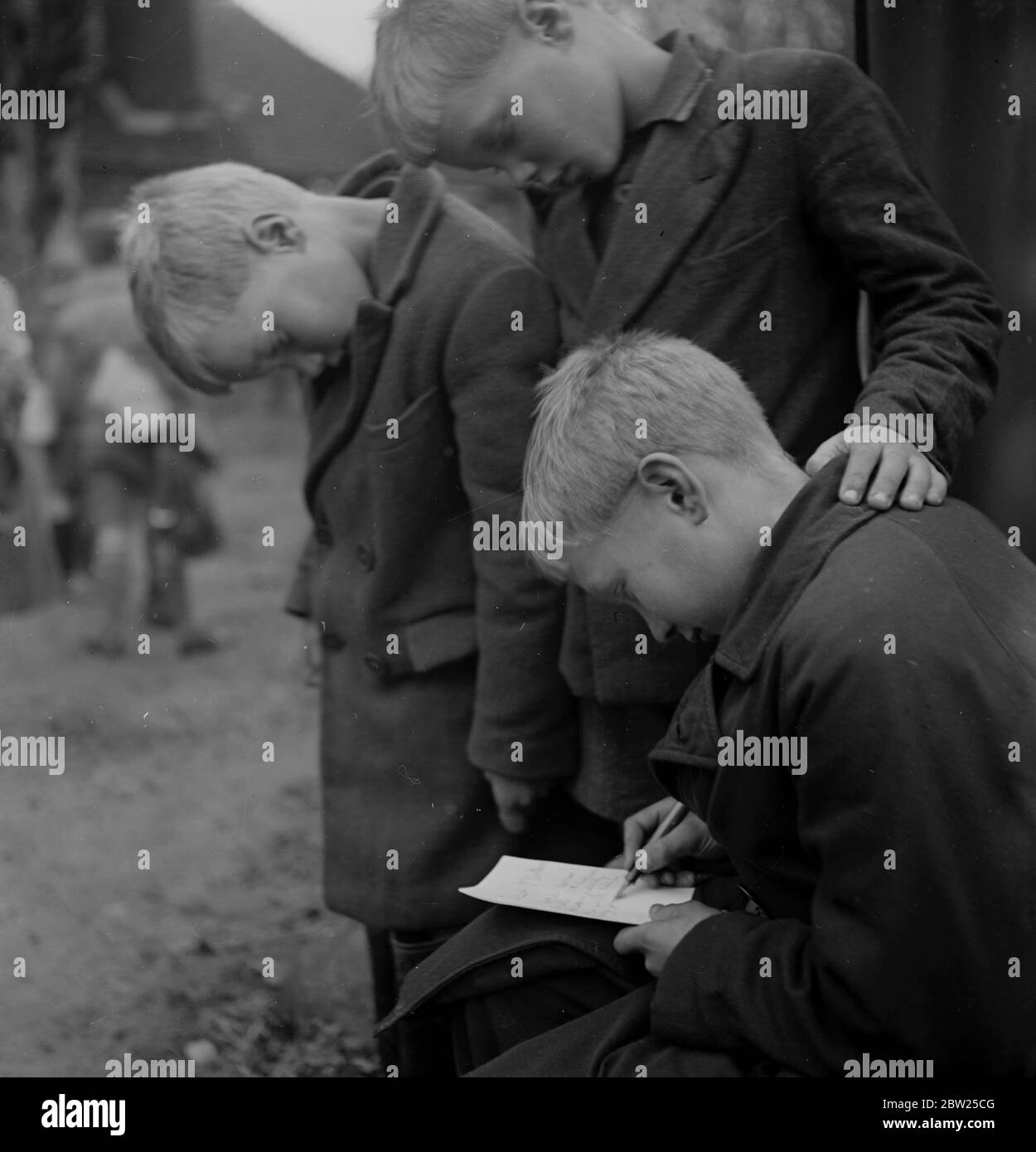 Les enfants de Cockney de la région de Sydenham Road de Croydon poussent dans les fermiers après leur évacuation dans la région de Woodingdean près de Brighton. Écrivant une maison à mère, les Twins Harold et John Margetts regardent leur frère Paul écrit sa lettre hebdomadaire. Banque D'Images