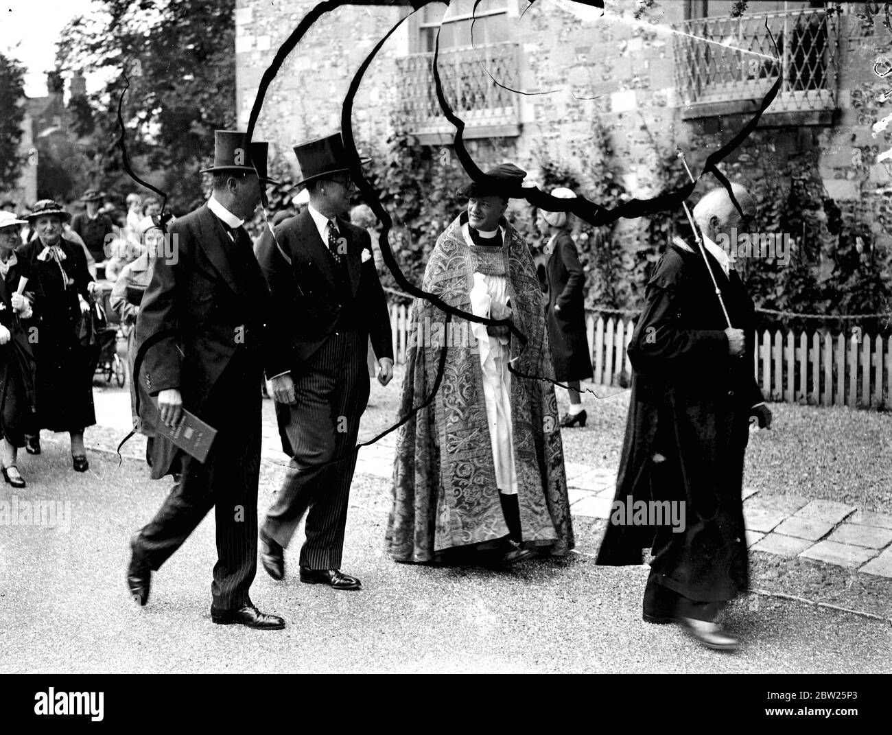 M. Joseph P Kennedy, ambassadeur américain, Dévoilée dans la cathédrale de Winchester, une vitrail qui a été donné à la cathédrale par les Américains en hommage à la vie et au caractère du roi George V. l'une des lumières contient une représentation de la figure à genoux du roi portant les robes de l'ordre de Le Garter'. La fenêtre est le travail de M. Hugh Easton. Photos, M. Joseph P Kennedy (centre) marchant vers la cathédrale avec Lord Mottistone, Lord Lieutenant de Hammshire (à gauche) et le doyen de Winchester, le très Rév Dr E G Salwyn (à droite, partiellement caché). 12 juillet 1938 Banque D'Images
